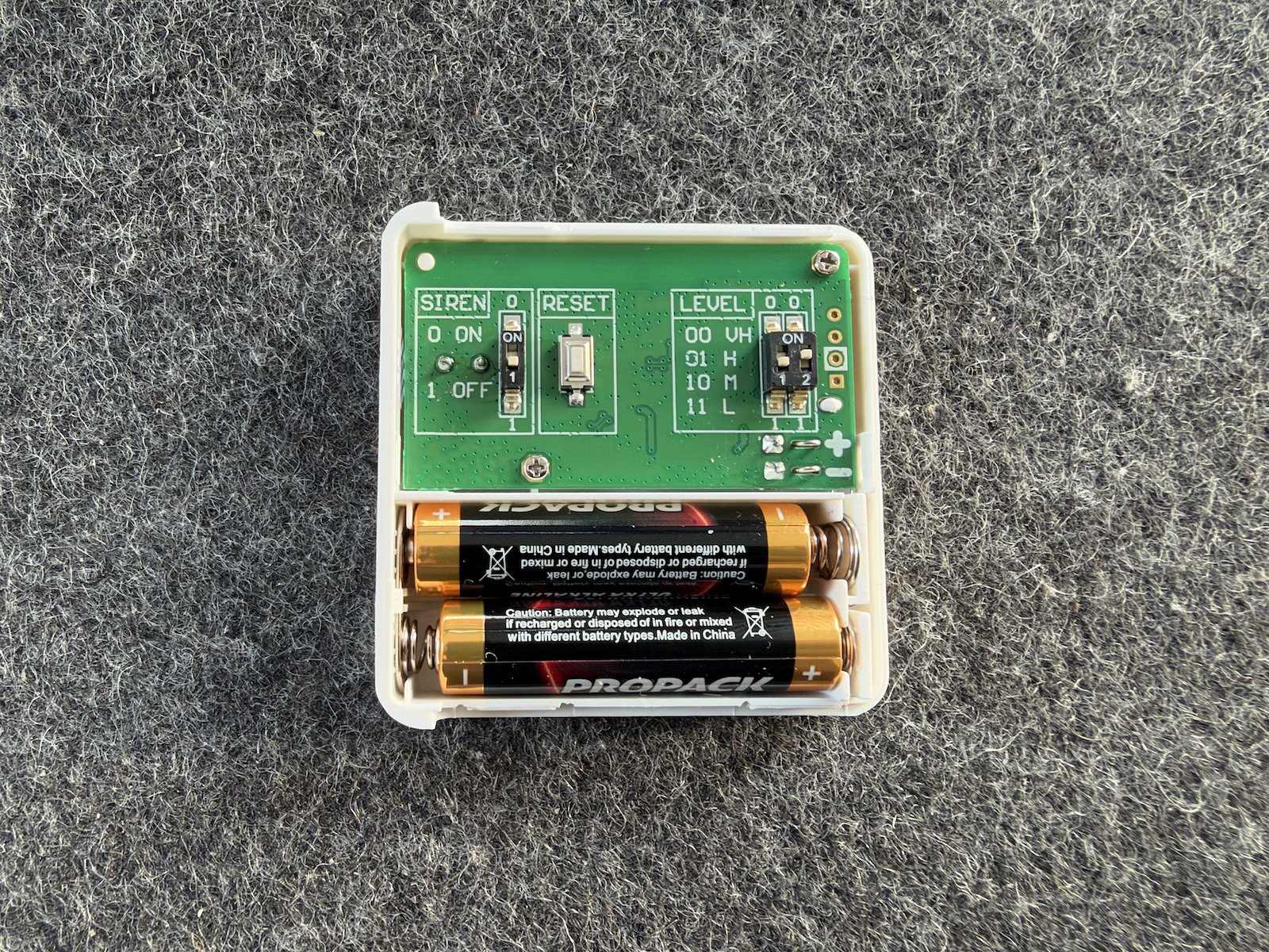 Geöffneter Neigungssensor mit DIP-Schalter für die Empfindlichkeit, Sirenen-Schalter und zwei AAA-Batterien