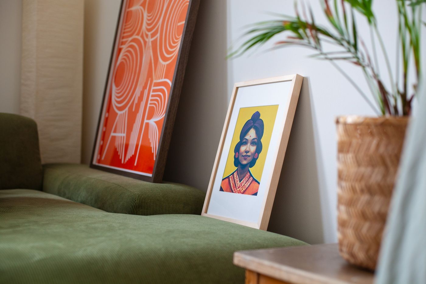 OpenPaper E-Ink-Bilderrahmen von paperlesspaper mit farbigem Porträt im Holzrahmen, angelehnt auf einem Sideboard neben einem grünen Sofa