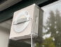 Ecovacs Winbot W2S Omni im Test: Der Fensterputzroboter haftet an einer Fensterscheibe, dahinter Bäume im Garten