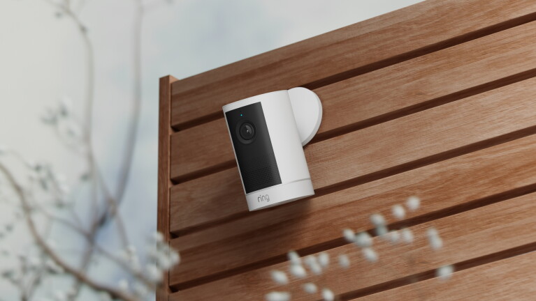 Weiße Ring Outdoor Camera 4K Plus an einer Außenwand aus Holzlamellen