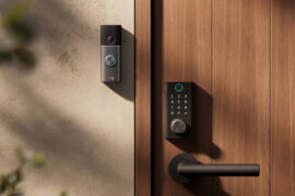 Ring Smart Lock mit Zahlenfeld und Drehknopf an einer Holztür, daneben eine Ring Türklingel an der hellen Hauswand