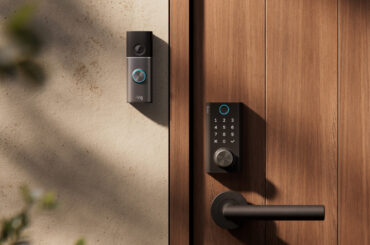 Ring Smart Lock mit Zahlenfeld und Drehknopf an einer Holztür, daneben eine Ring Türklingel an der hellen Hauswand